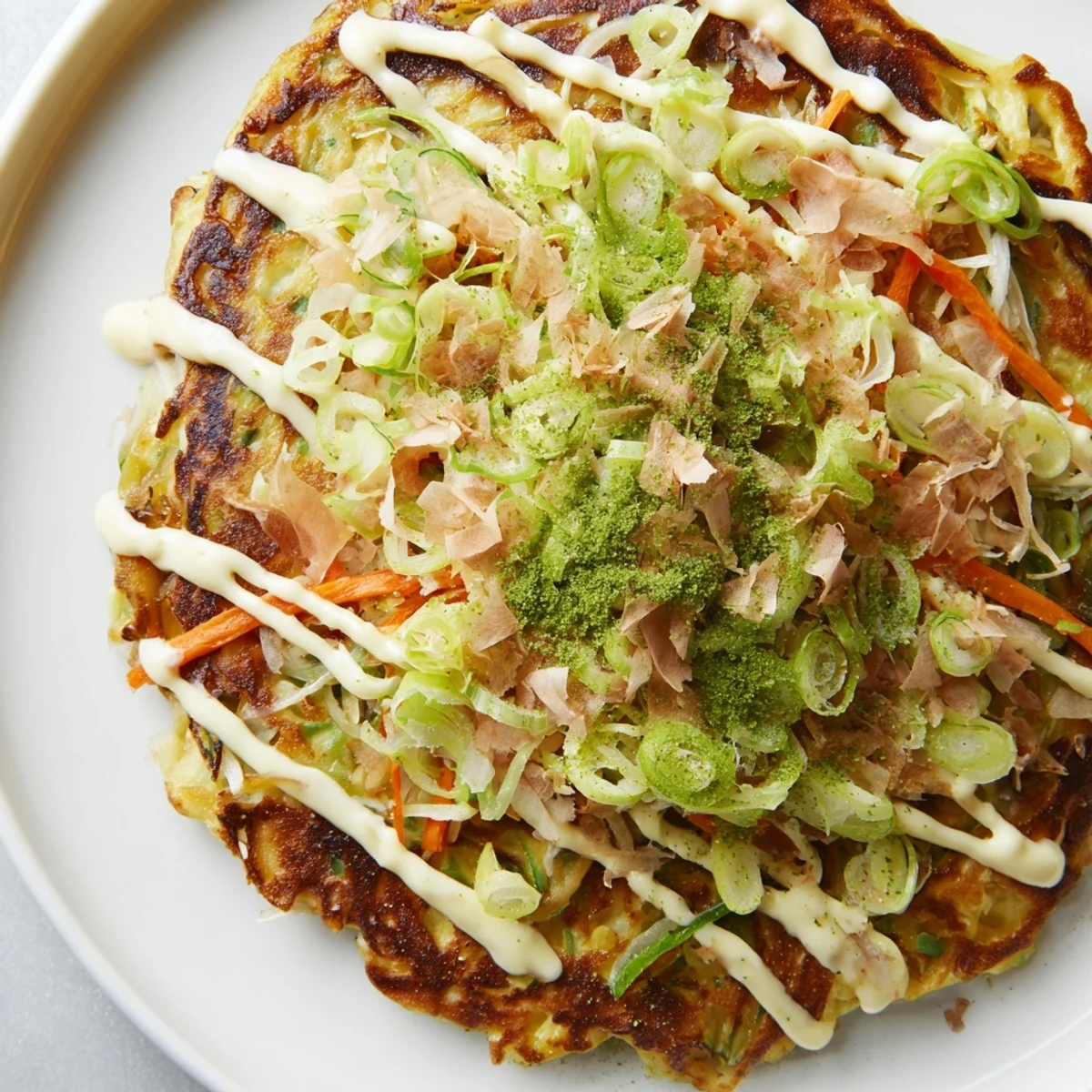 Close up of a delicious Japanese okonomiyaki pancake: savory, loaded with cabbage, and drizzled with mayo.