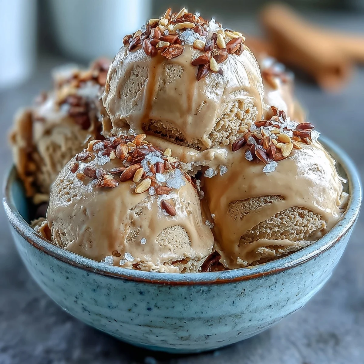 Creamy Hojicha Ice Cream scooped into a rustic bowl, topped with toasted sesame seeds for a nutty crunch.