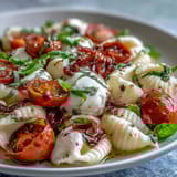 Fresh burrata and ripe cherry tomatoes top this easy Caprese pasta, fragrant with basil and a drizzle of olive oil.  