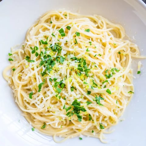 Steaming plate of Lemon Capellini with Fresh Herbs, its zesty sauce clinging to delicate pasta strands.