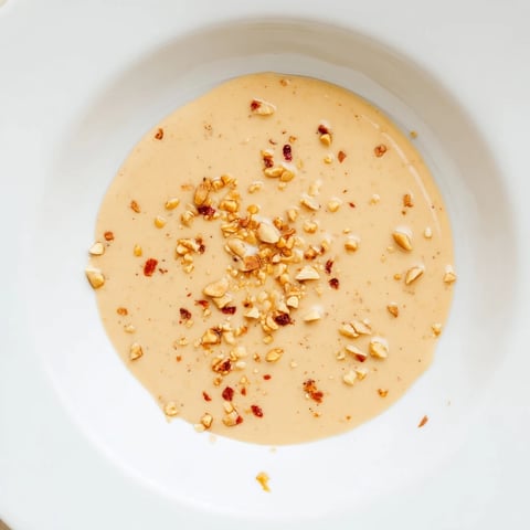 Creamy Indonesian satay sauce, ready to be drizzled, smells of peanuts and lime, a perfect dip.