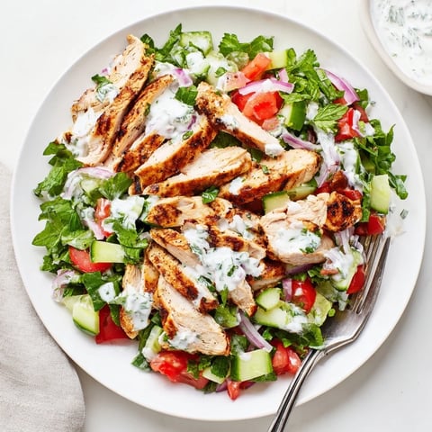 A vibrant Chicken Shawarma Salad with spiced grilled chicken, crisp cucumber, tomato, and greens, topped with creamy yogurt dressing.