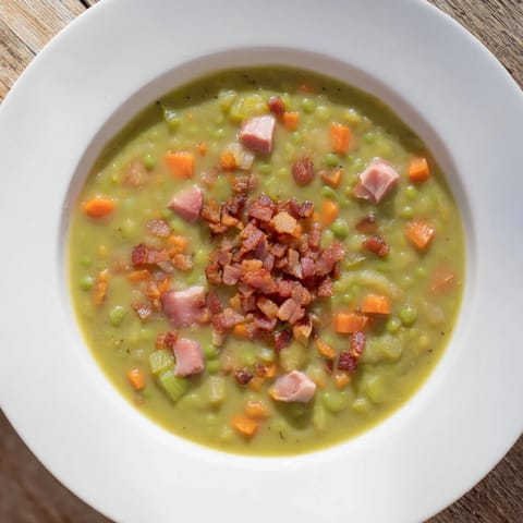 Close-up of hearty Split Pea Soup featuring chunks of ham and a sprinkle of bacon.