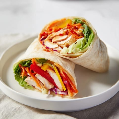 A close-up of a delicious teriyaki chicken wrap ready to eat, with fresh ingredients overflowing.