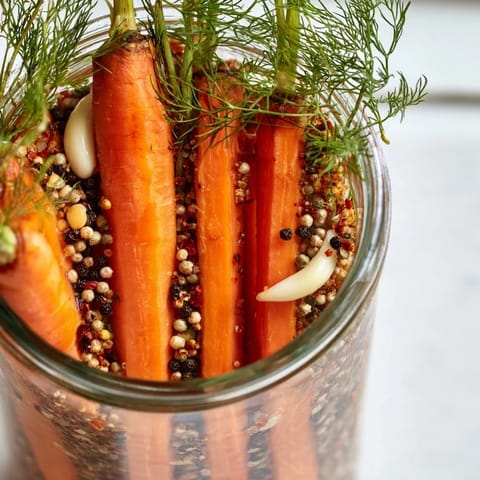 Close-up of Quick Pickled Carrot Spears, glistening in jar with garlic and peppercorns, delicious side.