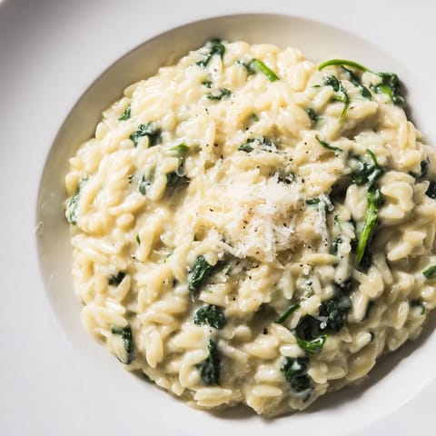 Delectable close-up of Creamy Spinach Orzo, showing creamy sauce around orzo and fresh spinach.
