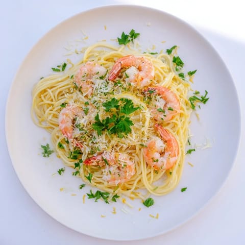 A serving of Lemon Garlic Shrimp Pasta garnished with fresh parsley and Parmesan, ready to enjoy with lemon wedges.