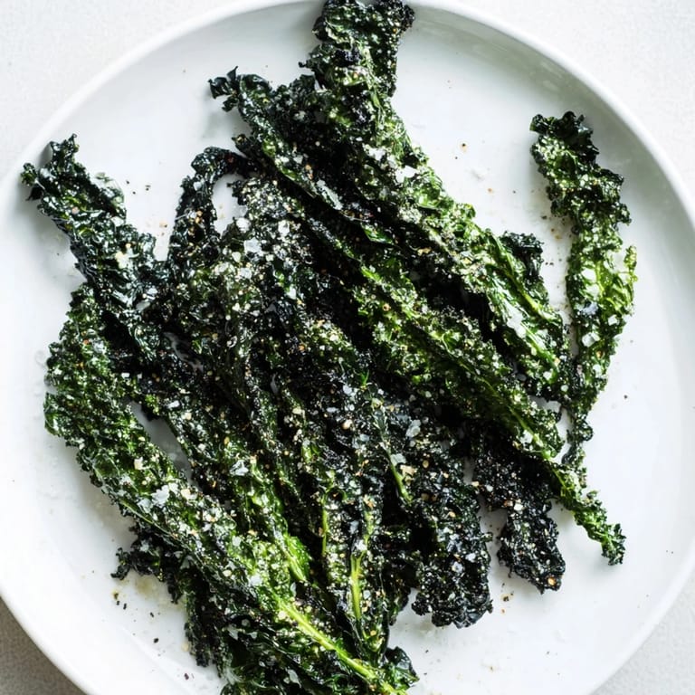 Close-up of freshly baked kale chips, perfectly seasoned and lightly salted, ready to crunch.