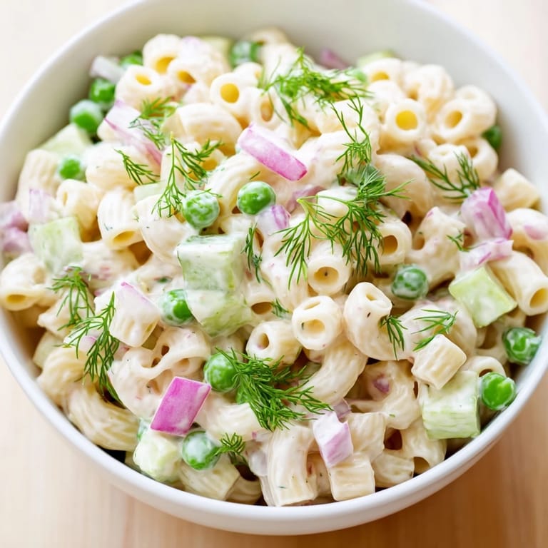 Chilled ditalini pasta salad with crunchy dill pickles, celery, and a creamy dressing, served in a white bowl.  