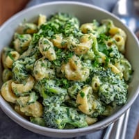 Vibrant green mac and cheese with spinach and broccoli, creamy and cheesy, served in a rustic cast-iron skillet.  