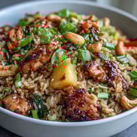 A colorful bowl of pineapple chicken fried rice with juicy pineapple chunks, tender chicken, crunchy cashews, and vibrant vegetables.